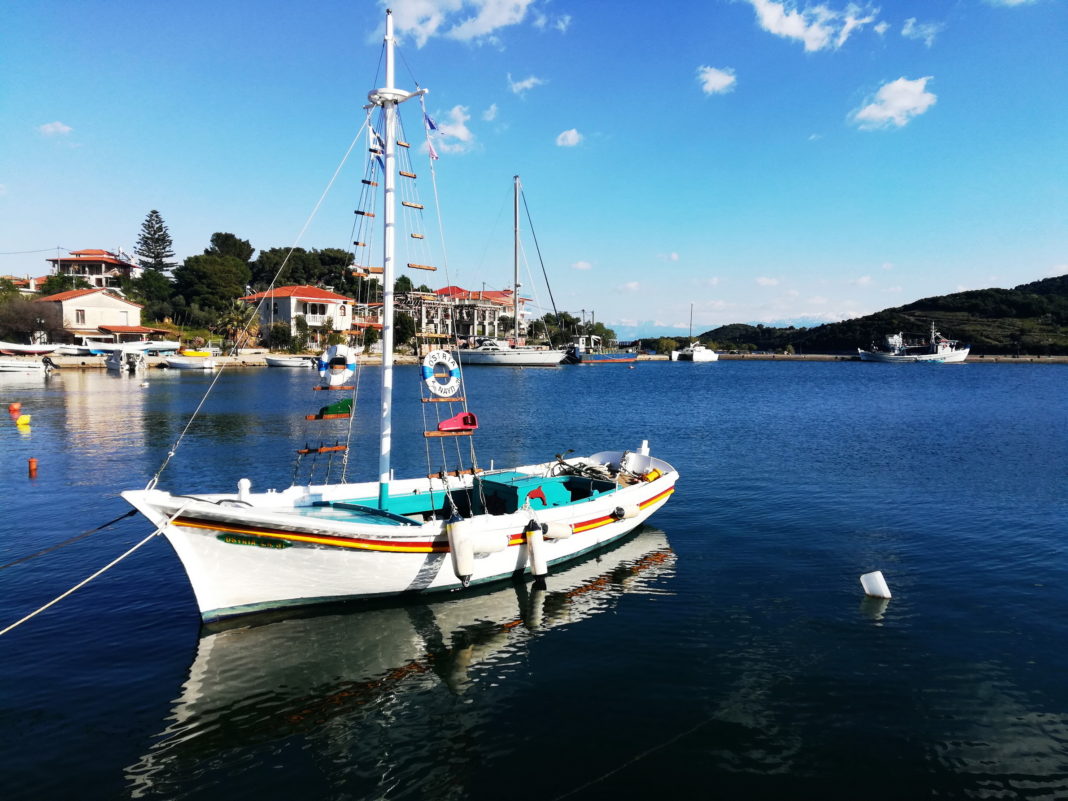 A colorful sailboat reflected in a glassy seain a