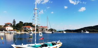 A colorful sailboat reflected in a glassy seain a