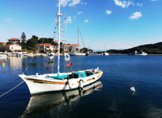 A colorful sailboat reflected in a glassy seain a