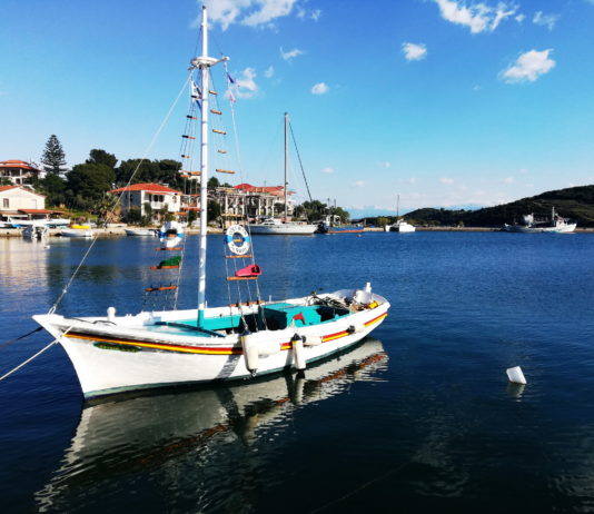 A colorful sailboat reflected in a glassy seain a