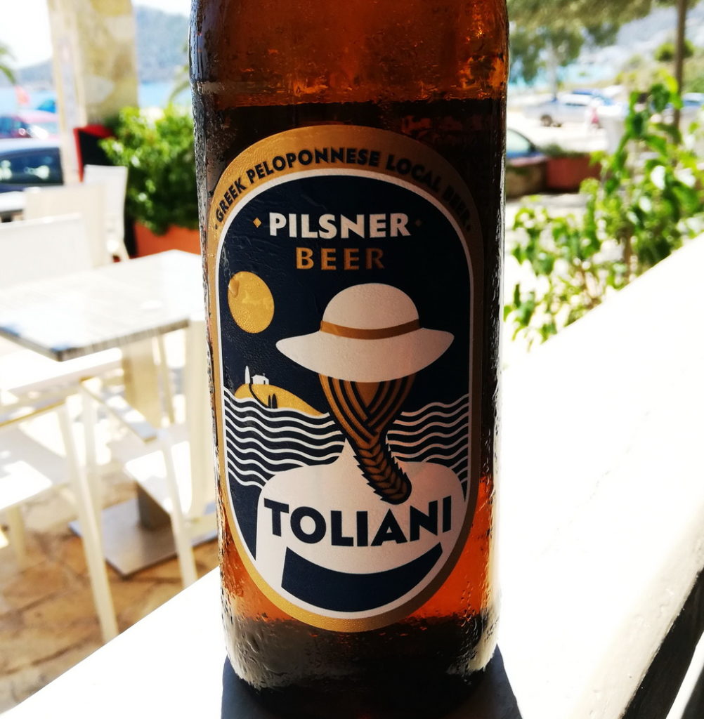 The Refreshing Ultra-local Pilsner - Toliani, has a sketch of a girl at the beach