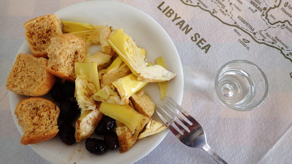 Great Greek drinks -a shot of tsicoudia with a plate of raw artichoke slices