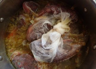 Fresh fish in cheesecloth simmers in apot of Greek fish soup - psarosoupa