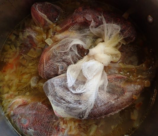 Fresh fish in cheesecloth simmers in apot of Greek fish soup - psarosoupa