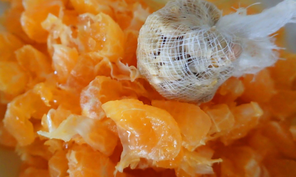 Mandarine segments with their pitch and juice, with the pits wrapped in gauze for thickening the jam.