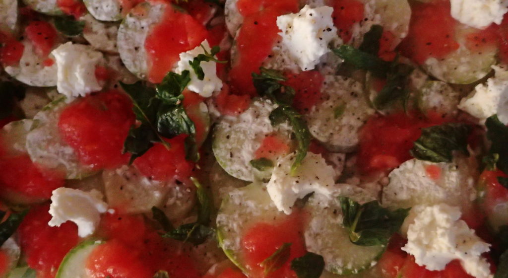 Layers of delicate slices of potato and zucchini are dotted with goat cheese and grated tomato, with fresh mint leaves