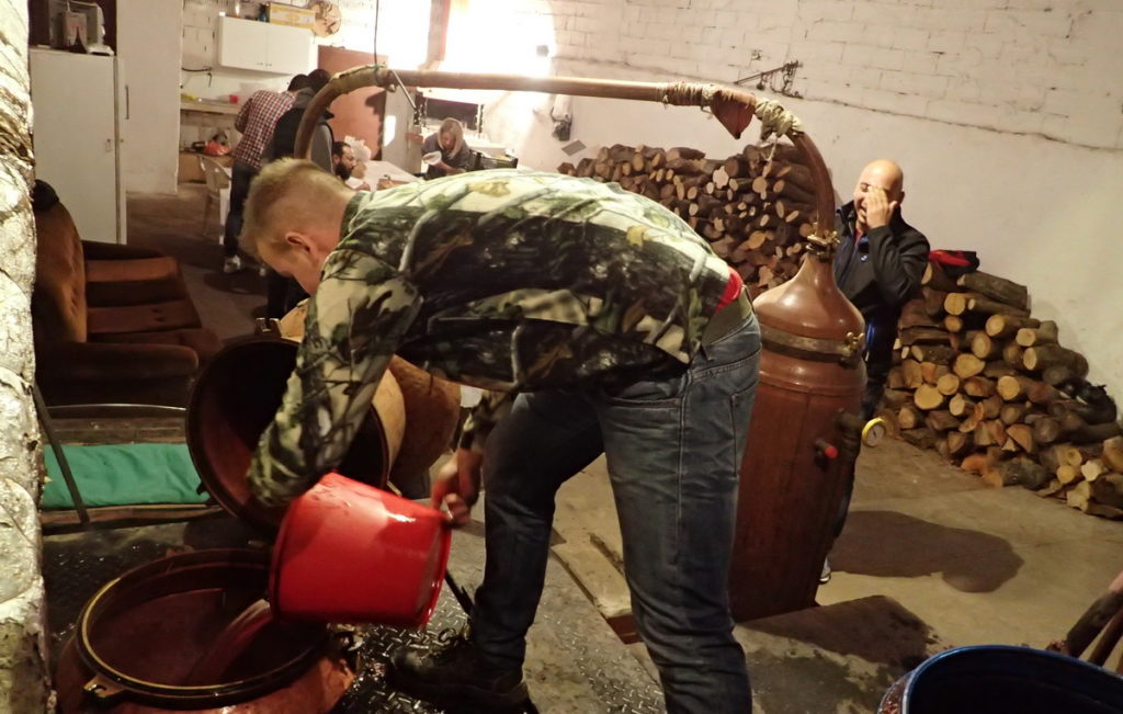 Filling the still with buckets of fermented grape mash