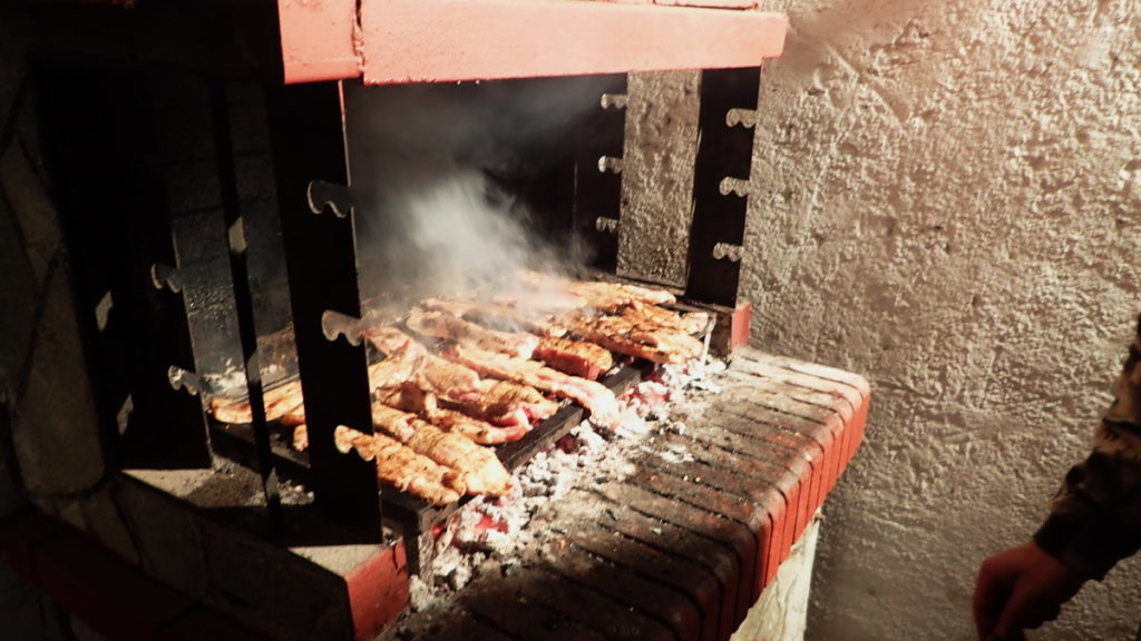 As the tsipouro distills, souvlakia char on the grill.