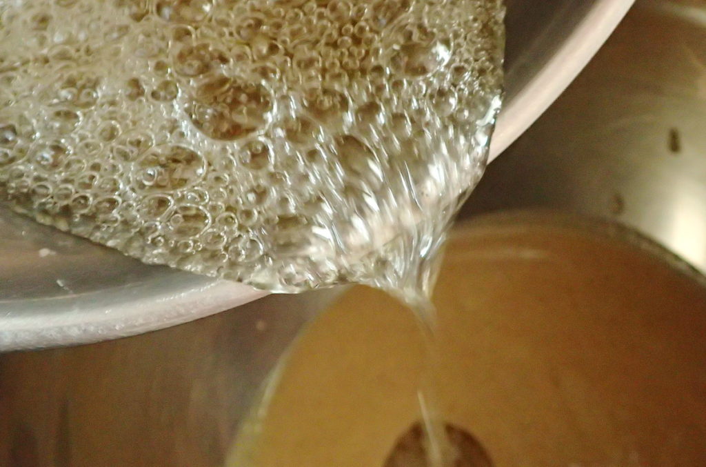 Adding the bubbling hot sugar syrup to the tahini is the first step in the halva recipe