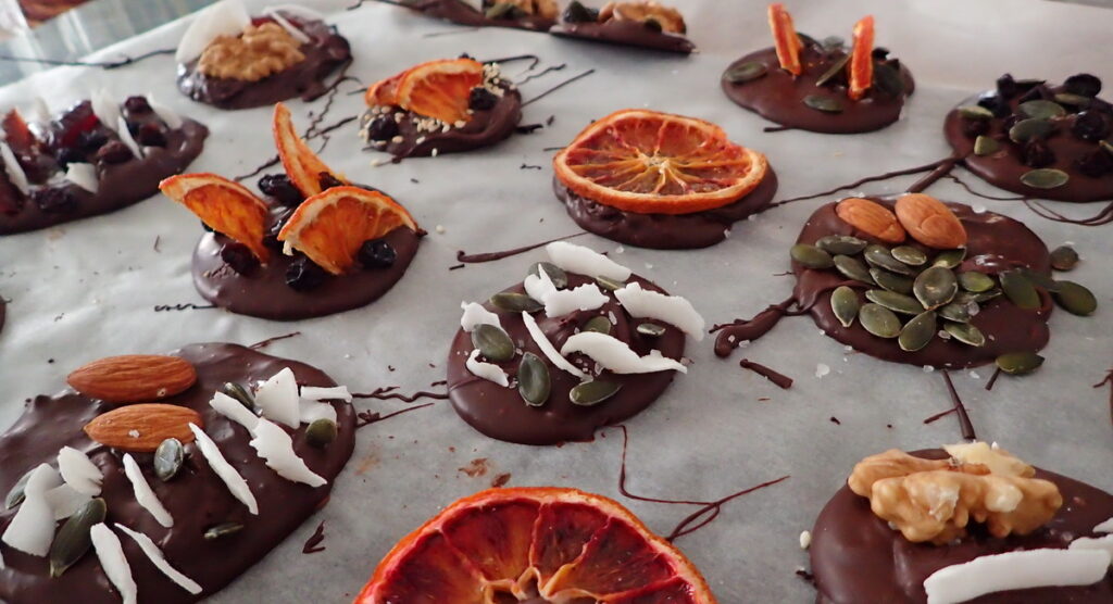 Mendiants Chocolat with a Variety of Toppings - dried orange slices, coconut, green pumpkin seeds