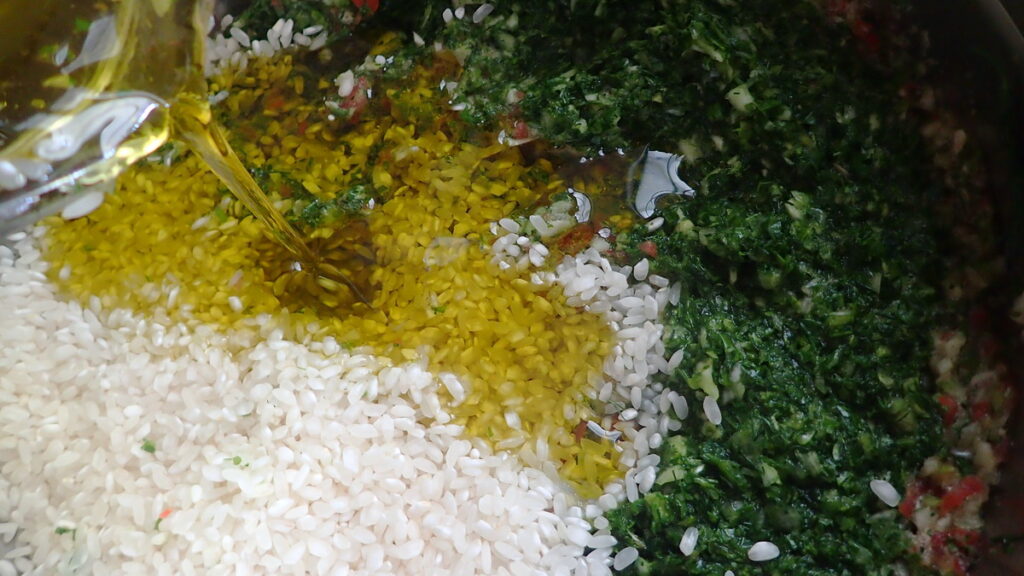 Pouring lots of extra virgin olive oil into the rice and herb mixture for stuffed grape leaves - dolmadakia gialantzi